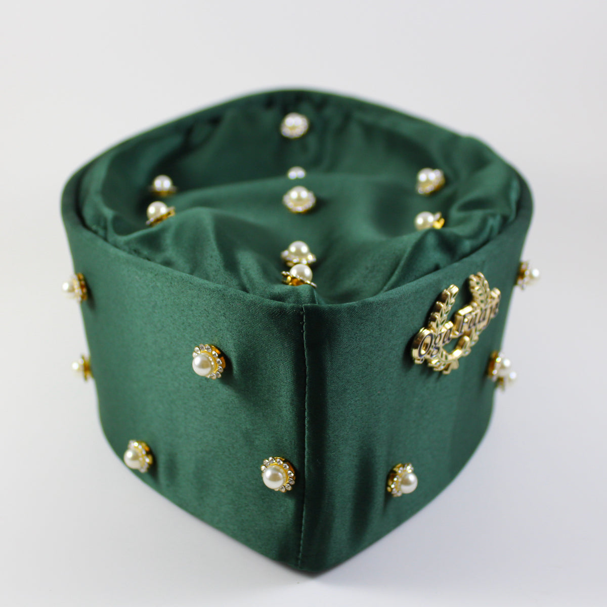A dark green satin skullcap adorned with gold and pearl decorative accents, photographed on a clean white background.